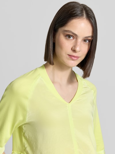 Kobiece modelka nosi T-Shirt mit V-Ausschnitt und 3/4-Arm von Marc Cain, mieszanka bawełny i elastanu, krój relaxed fit, dekolt w serek, długość tyłu w rozmiarze 36: 60 cm, jasny żółty kolor, prosta faktura, półmatowe wykończenie, zbliżenie górnej części ciała.