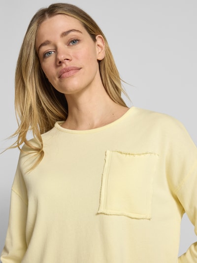 Frauenmodel trägt Sweatshirt mit Brusttasche von Rich & Royal in Gelb aus reiner Bio-Baumwolle, Rundhalsausschnitt, Loose-Fit, Nahaufnahme Oberkörper