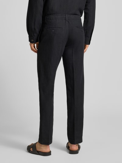 Männermodel trägt Straight Leg Leinenhose mit Tunnelzug Modell 'LEROY' von SELECTED HOMME in Schwarz, unifarben, Flammgarn, Ganzkörperansicht Rückansicht.