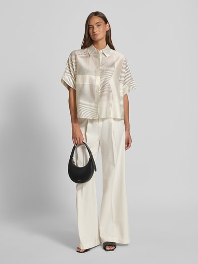 Vrouwenmodel draagt Boxy Fit blouse uit lyocellmix model 'Zulin' van Someday met overhemdkraag en bedekte knoopsluiting, crèmekleur met fijne strepen, lichte textuur, ruglengte 60 cm bij maat 36, mouwlengte 20 cm bij maat 36, boxy fit, vooraanzicht hele lichaam