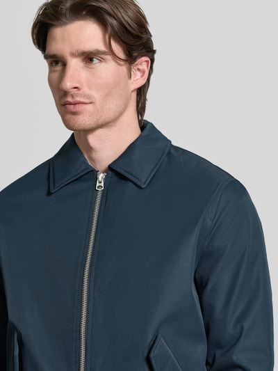 Männermodel trägt Jacke mit Reißverschluss von MCNEAL in Dunkelblau mit Kentkragen, Pattentaschen und gerippten Abschlüssen, Nahaufnahme Oberkörper.