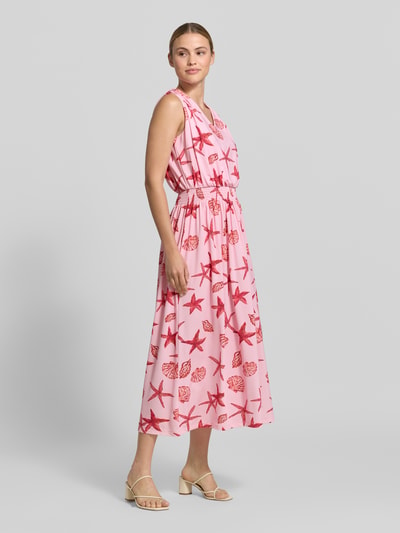 Frauenmodel trägt Damen Midikleid mit Allover-Motiv-Print von Milano Italy in Rosa mit Rot, Tailliert, V-Ausschnitt, Smok-Detail, Ganzkörperansicht von vorne.
