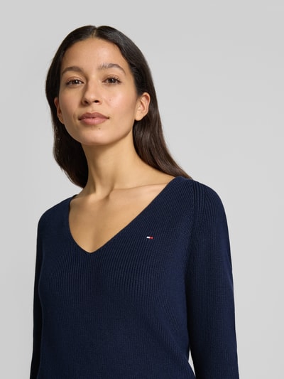 Kobiece modelka nosi Regular Fit Sweter z dzianiny z bawełny od Tommy Hilfiger, efekt: jednolity kolor, dekolt w serek, wyhaftowane logo, prążkowana dzianina, kolor granatowy, długi rękaw, raglanowe rękawy, Ganzkörperansicht von vorne.