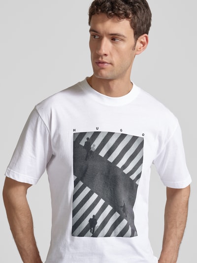 Männermodel trägt Slim Fit T-Shirt aus reiner Baumwolle Modell 'DODGER' von HUGO, Optik: unifarben, Motiv-Print, Nahaufnahme Oberkörper.