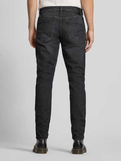 Mężczyznamodel nosi Jeans mit 5-Pocket-Design von G-Star Raw, bawełna z domieszką elastanu, krój slim fit, czarne, szerokość w rozmiarze 32/32: 41 cm, długość nogawki wewnętrznej: 81 cm, widok całej sylwetki z tyłu.