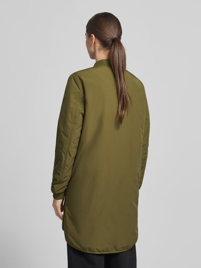 Frauenmodel trägt Jacke mit Zweiwege-Reißverschluss von camel active in Oliv, extralang, elastische Ärmel, lockere Passform, Ganzkörperansicht Rückansicht.