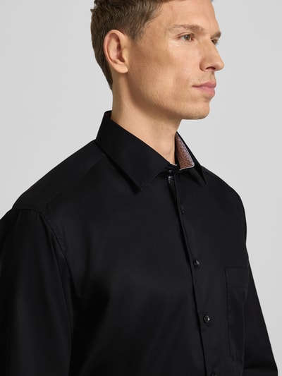 Mannelijk model draagt Comfort Fit Business Hemd aus Baumwolle mit Kentkragen van ETERNA in zwart, knoopsluiting, borstzak, close-up bovenlichaam.