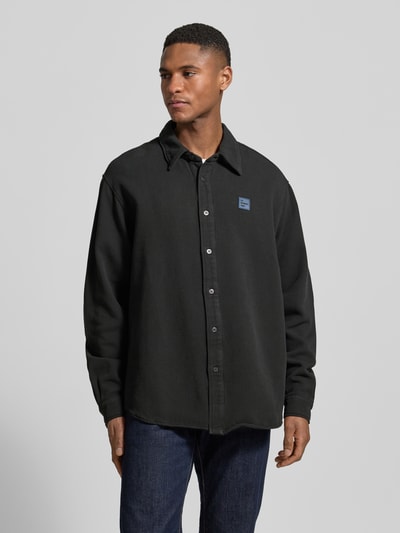 Männermodel trägt Regular Fit Freizeithemd mit Label-Patch von American Vintage in Schwarz, reine Baumwolle, Kentkragen, Knopfleiste, Ganzkörperansicht von vorne.