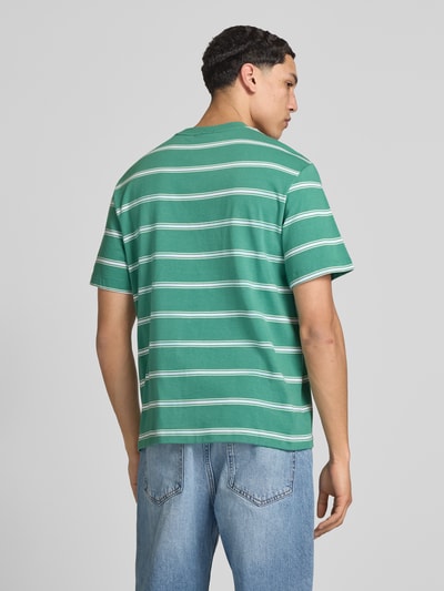 Männermodel trägt T-Shirt mit Logo-Stitching von Calvin Klein Jeans in Grün mit weißen Streifen, Reine Baumwolle, Gerader-Schnitt, Rückenlänge 69 cm, Ganzkörperansicht Rückansicht.