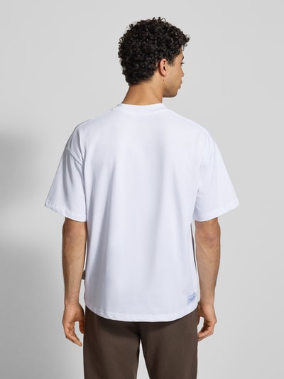 Männermodel trägt T-Shirt mit Label-Print von ANOTHER COTTON LAB in Weiß, Reine Baumwolle, Lockerer-Schnitt, Rückenlänge 73 cm, Ganzkörperansicht Rückansicht.