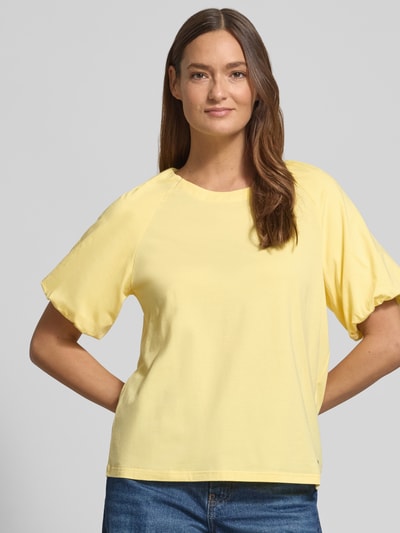 Vrouwenmodel draagt Regular Fit T-shirt met viscose-aandeel model 'Ruffel' van Fynch-Hatton, lichtgeel, ronde hals, elastische katoenmix, logodetail, ruglengte maat S 57 cm, close-up bovenlichaam vooraanzicht.
