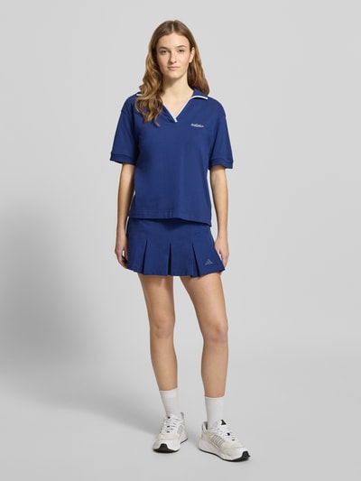 Frauenmodel trägt Ausgestellter Sportrock mit integrierten Tights von adidas Sportswear in Dunkelblau, Baumwolle, Logo-Stitching, Ganzkörperansicht von vorne.
