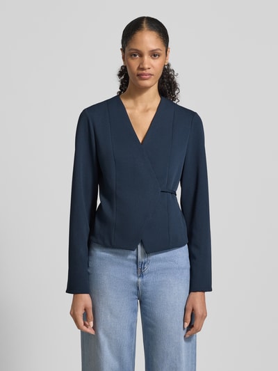 Frauenmodel trägt Blazer mit V-Ausschnitt Modell 'Simmi' von Neo Noir, Elastischer-Material-Mix, taillierte Passform, Wickel-Optik, Dunkelblau, glatte Textur, Bindeband, Rückenlänge 52 cm, Brustweite 40 cm, Ärmellänge 63 cm, Ganzkörperansicht von vorne.