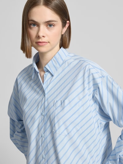 Frauenmodel trägt Relaxed Fit Bluse mit Brusttasche von JJXX in Hellblau mit Streifen, Reine Baumwolle, Hemdblusenkragen, Nahaufnahme Oberkörper. Modell 'JAMIE', Rückenlänge 78 cm, Ärmellänge 60 cm, Größe S.