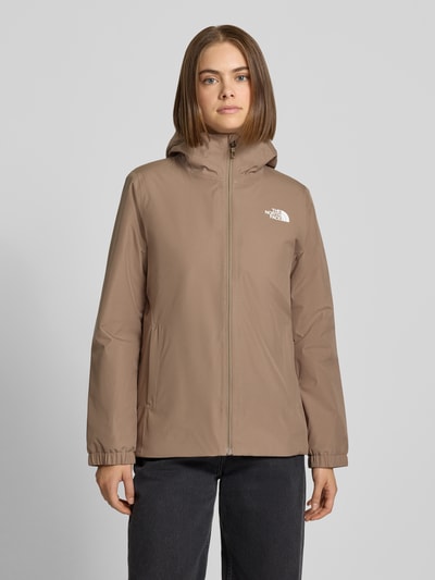 Frauenmodel trägt Regular Fit Funktionsjacke mit Logo-Print Modell 'Quest Mono' von The North Face in Beige, glatte Struktur, Ganzkörperansicht von vorne, Damen Funktionsjacken Kontext.
