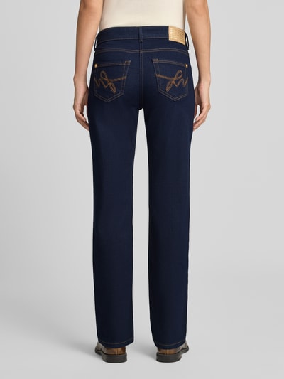 Frauenmodel trägt Straight Fit Jeans aus Baumwoll-Mix Modell 'Carrie' von MAC in dunklem Blau mit beigen Nähten, Ganzkörperansicht Rückansicht, Damen Straight Fit Jeans von MAC.
