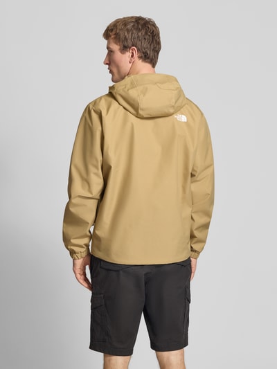 Männermodel trägt Jacke mit Kapuze von The North Face in Beige, Label-Print, Regular-Fit, Reißverschlusstaschen, Ganzkörperansicht Rückansicht. Rückenlänge 76 cm, Schulterbreite 48 cm, Brustweite 68 cm, Ärmellänge 68 cm, Größe L.