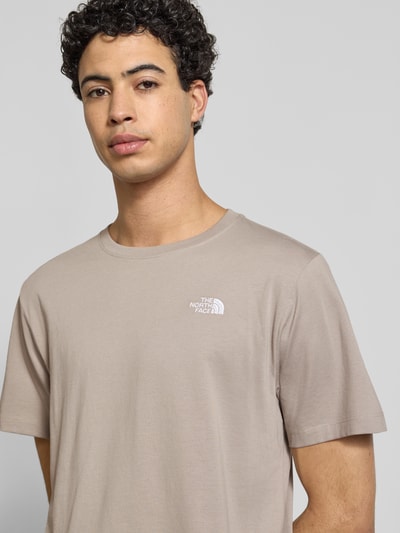 Männermodel trägt Regular Fit T-Shirt aus Baumwoll-Mix Modell 'EVOLUTION' von The North Face im Beige mit Label-Detail, Nahaufnahme Oberkörper.