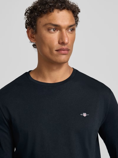 Männermodel trägt Longsleeve mit Label-Stitching von Gant in Schwarz, Reine Baumwolle, Regular-Fit, gerippter Rundhalsausschnitt, Nahaufnahme Oberkörper.