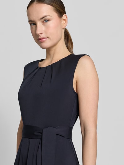 Kobiece model prezentuje Cocktailkleid mit Bindegürtel od Christian Berg Woman Selection, elastyczny materiał, krój taliowany, długość midi, okrągły dekolt, drapowania, pasek, długość tyłu w rozmiarze 36: 105 cm, szerokość w rozmiarze 36: 33 cm, zbliżenie na górną część ciała