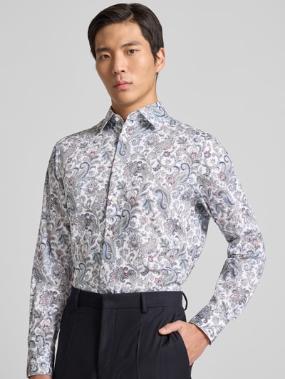Männermodel trägt Regular Fit Business Hemd aus reiner Baumwolle mit Kentkragen von OLYMP mit Allover-Paisley-Print, langärmelig, durchgehende Knopfleiste und Sportmanschetten, Rückenlänge 80 cm, Schulterbreite 48 cm, Ärmellänge 65 cm, Farben in Weiß, Blau und Grau, Ganzkörperansicht von vorne.