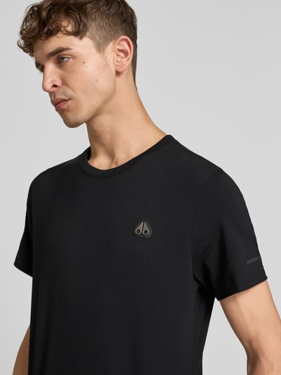 Männermodel trägt Regular Fit T-shirt met logodetail van Moose Knuckles, puur katoen, ronde hals, korte mouw, ruglengte maat M 67 cm, nahaufnahme bovenlichaam
