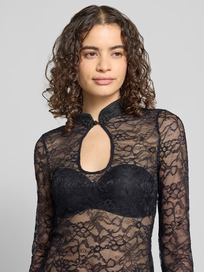 Frauenmodel trägt Slim Fit Longsleeve mit floraler Allover-Spitze von Gina Tricot, Elastischer-Material-Mix, Schlüsselloch-Ausschnitt, Langärmelig, Stehkragen, Semitransparent, schwarze Spitze, Rückenlänge bei Größe S 56 cm, Nahaufnahme Oberkörper.