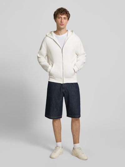 Männermodel trägt Regular Fit Sweatjacke mit Känguru-Tasche von REVIEW in Weiß, Baumwoll-Mix, Kapuze, Reißverschluss, Jeansshorts, Ganzkörperansicht von vorne.