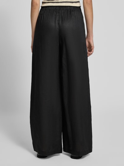 Frauenmodel trägt Wide Leg Leinenhose mit elastischem Bund Modell 'MOSSI' von ECOALF, Reines Leinen, schwarze Farbe, Ganzkörperansicht Rückansicht.