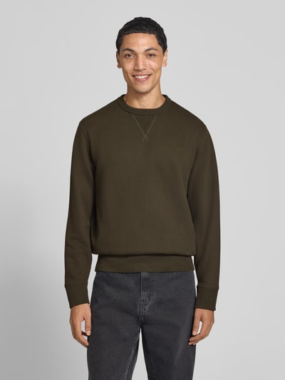 Männermodel trägt Sweatshirt aus Baumwoll-Mix von Superdry in Dunkelgrün mit Rundhalsausschnitt und elastischen Abschlüssen, Ganzkörperansicht von vorne.