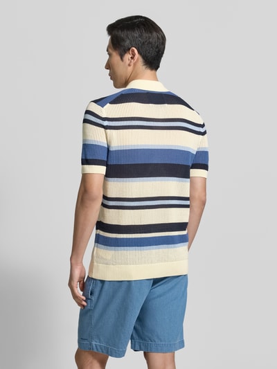 Mannelijk model draagt Slim Fit poloshirt in tricotlook van Gant, puur katoen, polokraag, met korte mouwen, ruglengte maat M 71 cm, geheel gestreept in beige, blauw en zwart, geheel gestreepte textuur. Ganzkörperansicht Rückansicht.