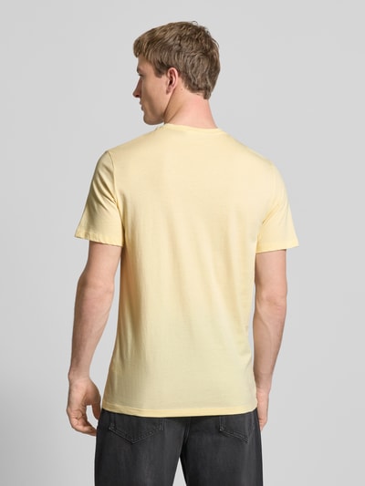 Männermodel trägt T-Shirt mit Label-Badge von Calvin Klein Jeans in Gelb, Reine Baumwolle, Regular-Fit, Rundhalsausschnitt, Rückenlänge 70 cm, Ganzkörperansicht Rückansicht.