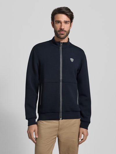 Männermodel trägt Sweatjacke mit Reißverschluss von EA7 Emporio Armani, Regular-Fit, Stehkragen, Label-Detail, Eingrifftaschen, dunkelblau, Vorderansicht, Nahaufnahme Oberkörper.