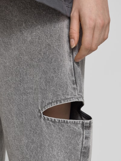 Frauenmodel trägt Mom Fit Jeans mit Cut Out von Karo Kauer aus Reine Baumwolle im 5-Pocket-Design, graue Textur, Nahaufnahme Oberschenkel.