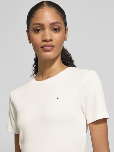 Frauenmodel trägt Slim Fit T-Shirt aus reiner Baumwolle von Tommy Hilfiger in Unifarbe mit Logo-Stitching, Nahaufnahme Oberkörper.