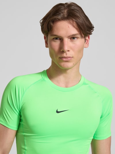 Männermodel trägt T-Shirt mit Logo-Print und Rundhalsausschnitt von NIKE TRAINING in Slim-Fit mit Raglanärmel, Nahaufnahme Oberkörper.