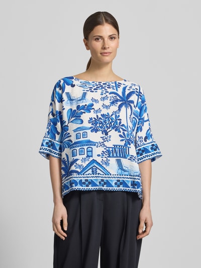 Kobiece model prezentuje Regular Fit Bluse aus Viskose-Mix von Christian Berg Woman, mieszanka wzorów na całej powierzchni, listwa guzikowa, rękaw o dł. 1/2, okrągły dekolt, długość tyłu w rozmiarze 36: 55 cm, długość rękawów w rozmiarze 36: 30 cm, niebieskie i białe barwy, widok całej sylwetki od przodu