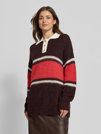 Frauenmodel trägt Strickpullover aus Woll-Alpaka-Mix von Closed in Braun, Rot und Weiß mit Polokragen, lockerer Passform, Nahaufnahme Oberkörper.