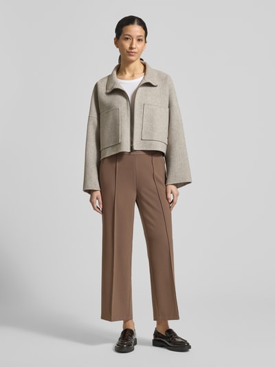 Modelka nosi spodnie materiałowe Straight Fit z ozdobnym szwem model 'Cameron' od Cambio, skrócony krój, kieszenie z tyłu, elastyczny pas, nadruk z logo, szerokość w rozmiarze 36: 39 cm, długość wewnętrzna nogawki w rozmiarze 36: 67 cm, widok całej sylwetki z przodu.