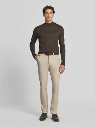 Männermodel trägt Slim Fit Chino aus Baumwoll-Mix Modell 'Chino Slim 2' von BOSS Orange in Beige, gerade Form, Ganzkörperansicht von vorne.