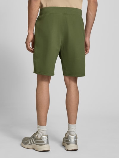 Männermodel trägt Straight Fit Shorts mit Strukturmuster von G-Star Raw, grün, Elastischer-Material-Mix, Logo-Detail, Ganzkörperansicht Rückansicht.