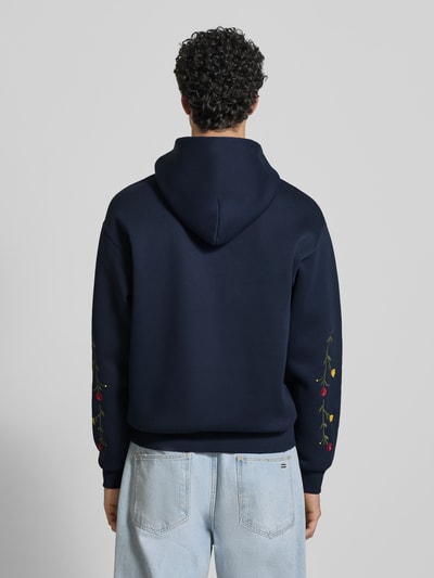 Männermodel trägt Regular Fit Hoodie mit Logo-Stitching von REVIEW in Dunkelblau mit floralen Stickereien, Rückenansicht, Baumwoll-Mix.