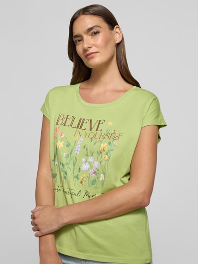 Frauenmodel trägt T-Shirt mit Motiv-Print und Rundhalsausschnitt von Christian Berg Woman aus Baumwoll-Viskose-Mix, Regular-Fit, Damen T-Shirt in hellem Grün mit floralen Farbakzenten, Motiv-Print und Rundhalsausschnitt, Rückenlänge bei Größe S: 56 cm, Nahaufnahme Oberkörper.