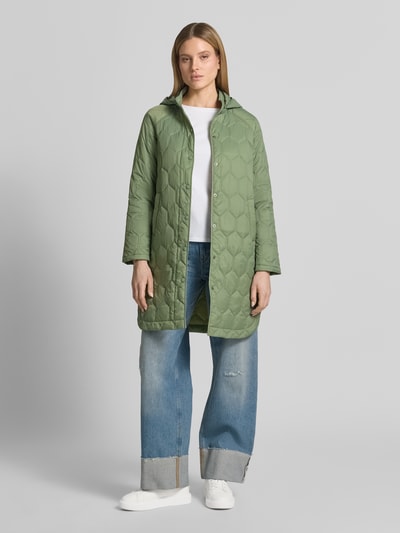 Frauenmodel trägt Regular Fit Mantel in Stepp-Optik Modell 'Solene' von CARS JEANS in Grün, Stehkragen mit Kapuze, Eingrifftasche, durchgängige Knopfleiste, Rückenlänge bei Größe S 95 cm, Schulterbreite 42 cm, Brustweite 53 cm, Ärmellänge 47 cm, Ganzkörperansicht von vorne.