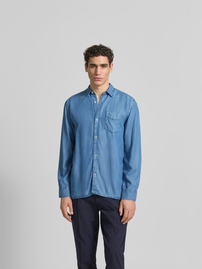 Männermodel trägt Relaxed Fit Jeanshemd aus reinem Lyocell von Officine Générale, Blau, durchgehende Knopfleiste, Brusttasche, Langärmelig, Ganzkörperansicht von vorne. Rückenlänge bei Größe M: 76 cm, Schulterbreite: 45 cm, Ärmellänge: 66 cm.