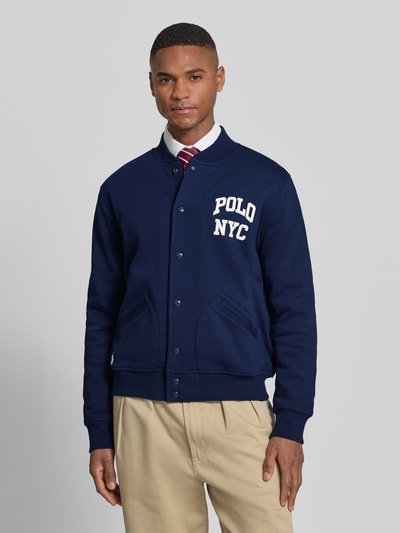 Männermodel trägt Regular Fit College-Jacke aus Baumwoll-Mix von Polo Ralph Lauren, Optik: Unifarben, Navy, Druckknöpfe, Ganzkörperansicht von vorne