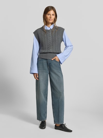 Frauenmodel trägt Regular Fit Pullunder mit Woll-Anteil von MYON in Grau, Strick-Optik, kombiniert mit blauer Bluse und Jeans, Ganzkörperansicht von vorne. Material-Mix mit Woll-Anteil, Rundhalsausschnitt, Rückenlänge Größe 36: 56 cm.