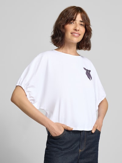 Frauenmodel trägt T-Shirt mit Motiv-Print und Kordelzug am Ärmel von Rich & Royal in Weiß, Loose Fit, reine Baumwolle, Nahaufnahme Oberkörper.