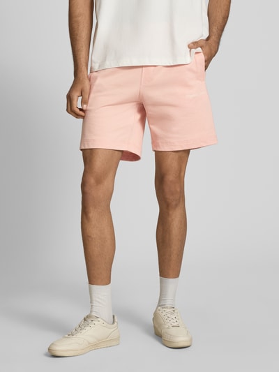 Männermodel trägt Sweatshorts mit Stitching Modell 'KARL' von Jack & Jones, rosafarbener Baumwoll-Mix, Regular Fit, Ganzkörperansicht von vorne.