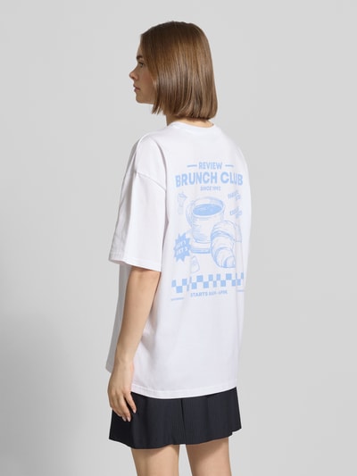 Frauenmodel trägt Oversized T-Shirt mit Statement-Print von REVIEW aus reiner Baumwolle, Damen T-Shirt, Oversize Fit, Rundhalsausschnitt, Rückenlänge bei Größe S 70 cm, Ganzkörperansicht Rückansicht.